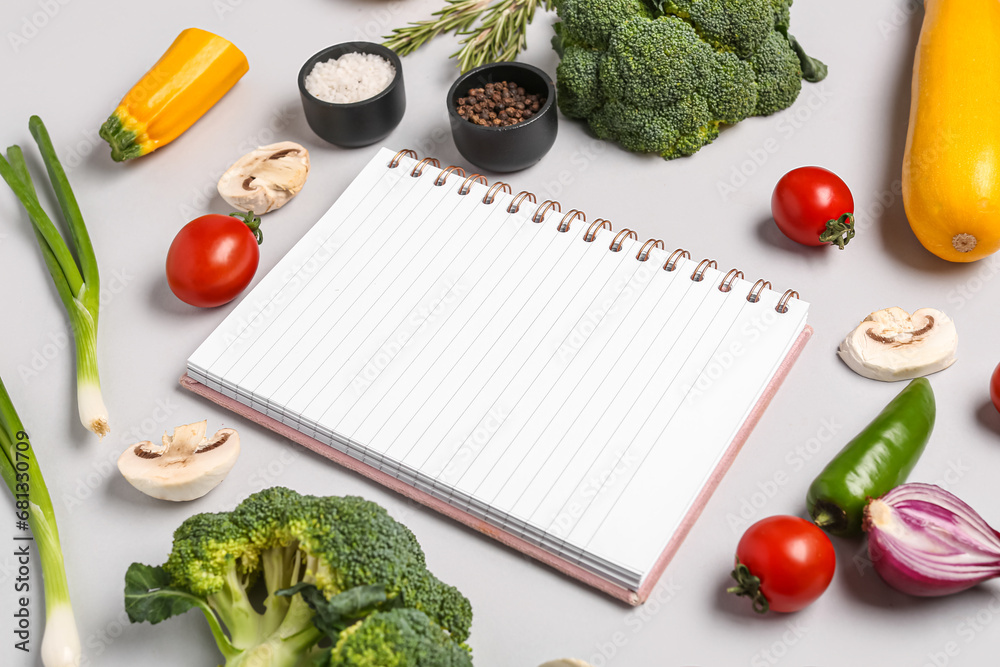Composition with blank recipe book, fresh vegetables and spices on grey background