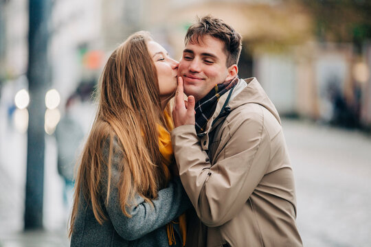 Girlfriend kissing on boyfriend's cheek at street