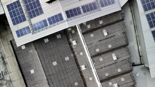 Aerial of large building on industrial terrain with a lot of solar panels on roof.
