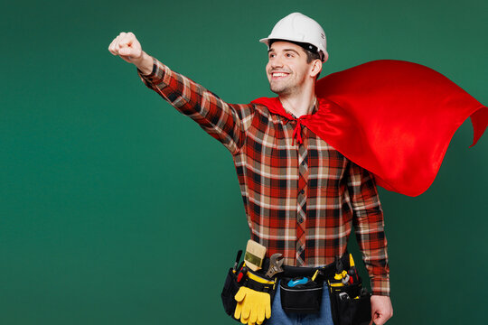 Young employee laborer man wear red shirt hardhat hat costume work do super hero gesture isolated on plain green background. Instruments accessories for renovation apartment room. Repair home concept.