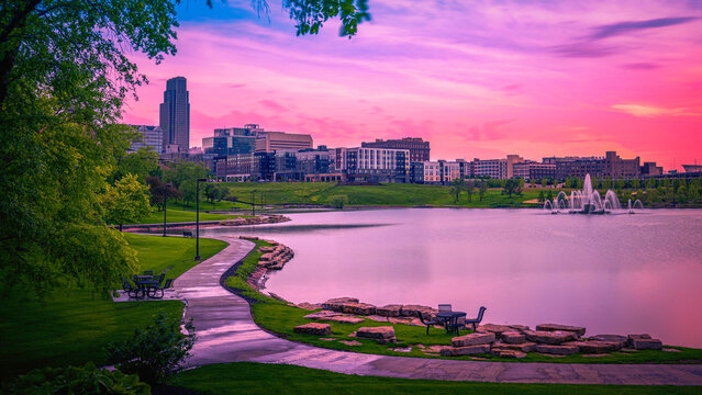 Omaha City Skyline at Sunrise over the Conagra Lake and vibrant green forest at the Heartland of America Park: The tranquil beauty of the midwestern metropolis in Nebraska