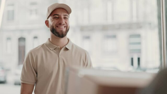 A friendly delivery man in a cap smiling as he hands over a package to a customer, capturing a moment of good service.