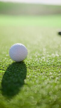 Close up of a golf club hitting a ball on the course. Vertical