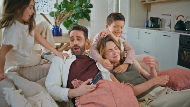 Happy family embracing sofa at home closeup. Funny kids hugging parents at couch