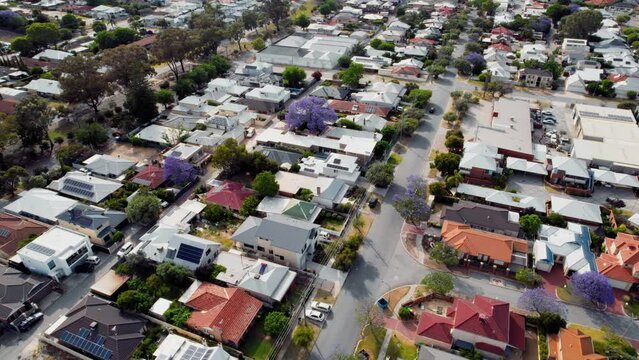 An aerial view of a suburban neighborhood in Perth, Australia, showcasing a mix of single-family homes and lush green trees.