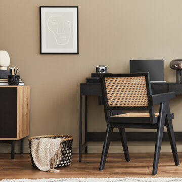 家庭办公空间的现代室内设计，配有时尚椅子、书桌、五斗柜、黑色模拟海报框、笔记本电脑、书籍、办公收纳用品以及家居装饰中精致的个人配饰。模板。