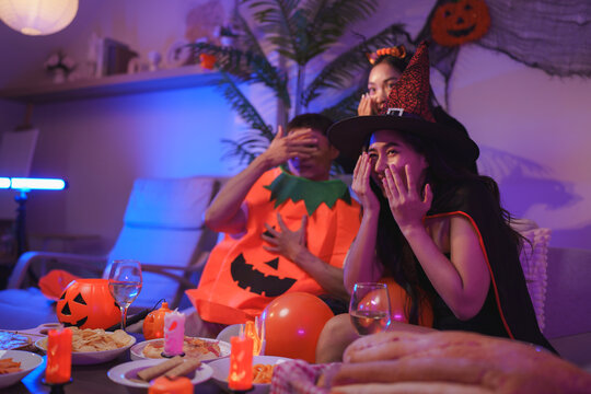 Young friends enjoying halloween party watching scary movie