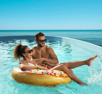 一对情侣在可俯瞰无边海景的泳池中尽情嬉戏