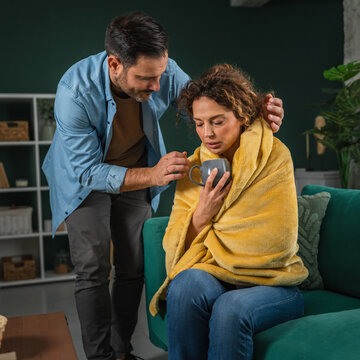 Partner caring for sick woman offering hot drink