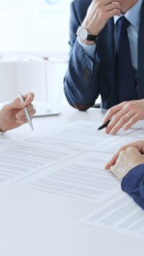 Business colleagues reviewing contract documents during an office meeting, discussing terms, and preparing for agreement signing, focusing on legal consultation and partnership discussion
