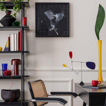 工作场所内饰，有模拟海报框架、黑色书桌、藤椅、时尚置物架、书籍、插着叶子的黄色花瓶、现代雕塑、带有灰泥装饰的墙壁以及个人配饰。家居装饰模板。