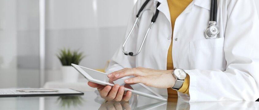 医生在诊所使用平板电脑处理数字健康数据、患者记录及医疗应用程序。医学、医疗保健与科学概念