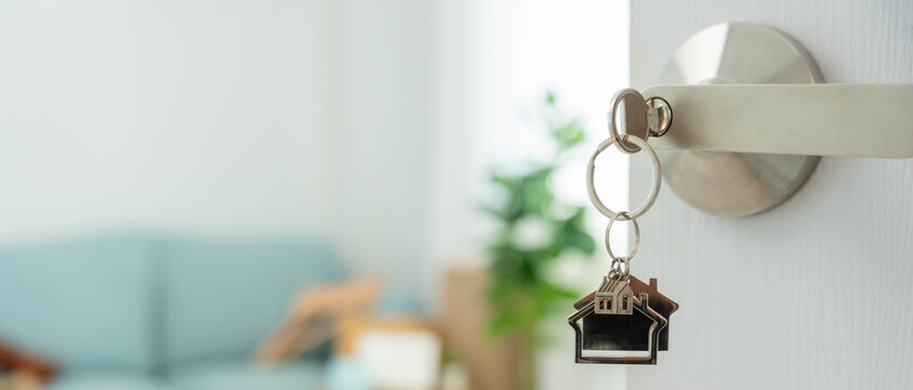 搬家，乔迁。钥匙插入新房的门，屋内有装着个人物品和家具的纸箱。搬进公寓或共管公寓