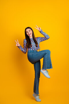 Playful young Latina woman poses confidently in a bright yellow studio background showcasing fashion style