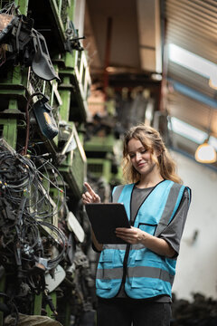 高加索人种女性工程师或机械师在汽车零部件仓库使用平板电脑检查汽车零部件