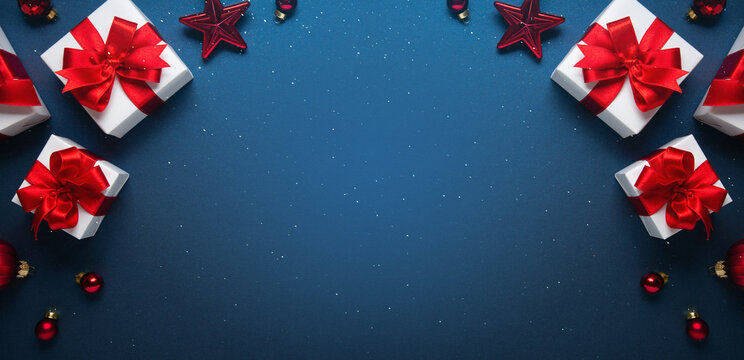 Merry Christmas and Happy Holidays greeting card, frame, banner. New Year. Noel. Red and white Christmas decorations and gifts on blue background top view. Winter xmas holiday celebration theme.