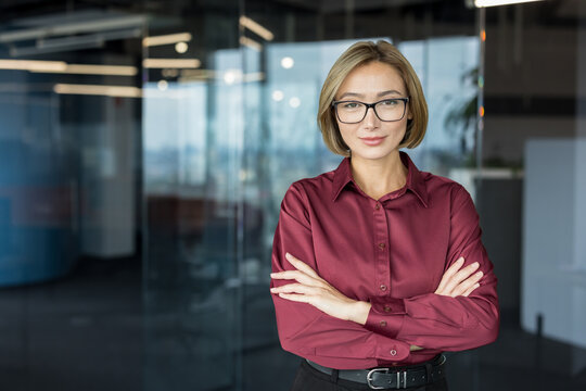 Professional businesswoman standing confident and smiling with arms crossed in a modern office, representing success, management, and corporate leadership