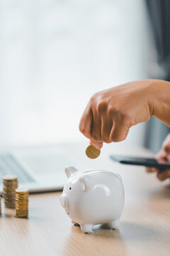 存钱与投资规划的概念。一位女商人将硬币投入办公桌上放着文件的白色存钱罐，象征着财务安全、预算管理与未来财富。