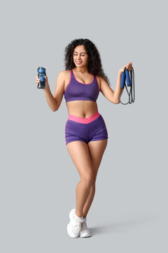 年轻活力的非裔美国女教练，手持跳绳和水瓶，白色背景