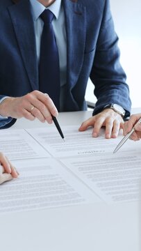 Business colleagues reviewing contract documents during an office meeting, discussing terms, and preparing for agreement signing, focusing on legal consultation and partnership discussion