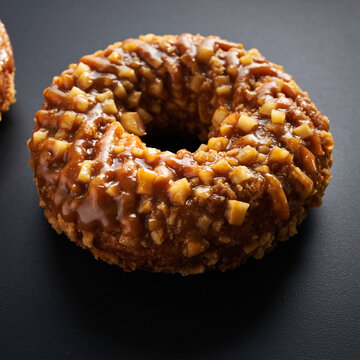 深色背景上带光泽坚果和焦糖糖衣甜甜圈特写