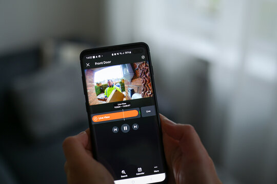 一名女子使用智能手机应用观看送货员投递包裹的特写镜头