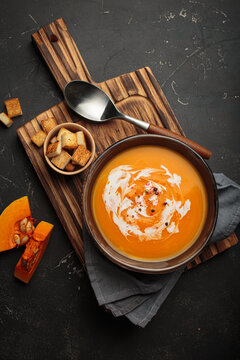 碗中盛着奶油南瓜汤，上面点缀着酥脆的面包丁和一圈鲜奶油，是秋季的理想之选，俯视图