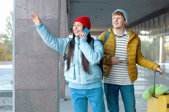 秋日，一对带着行李的年轻夫妇在机场附近用手机交谈