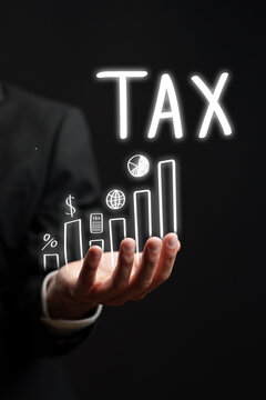 Businessman illustrating tax growth through a glowing graph in a dark setting