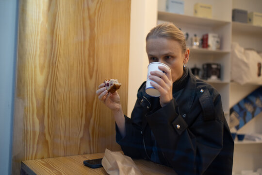 Woman enjoying coffee and pastry in cafe