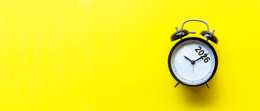 黄色背景上显示2025和2026的黑色闹钟，圣诞快乐和新年快乐主题。预留文案空间和横幅。