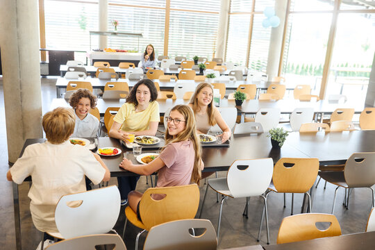 Group of students enjoying lunch together in a bright school cafeteria