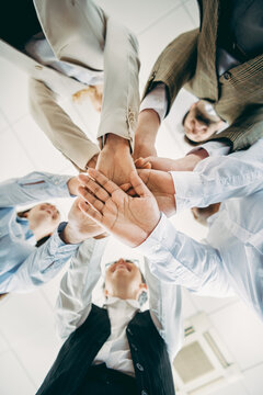 Business professionals join hands in a gesture of teamwork and unity, showcasing collaborative spirit and workplace harmony
