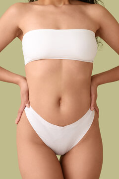 Beautiful young African-American woman with stretch marks on her body against green background, closeup