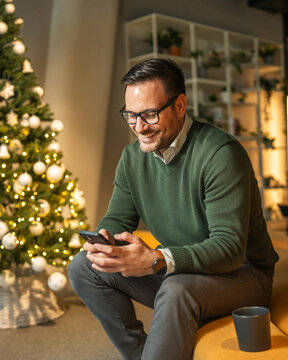 Man smiling using phone during christmas holiday in office