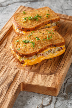 Breakfast Tuna Melt sandwich made of rye bread, canned tuna and melted cheese close-up on a wooden board on the table. Vertical