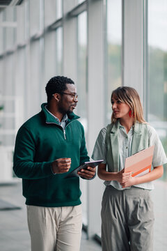 Business colleagues collaborating during a walk in office hallway