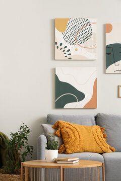 Cozy sofa with modern pictures and coffee table in living room